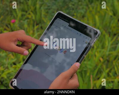 close up of hand holding smartphone opening google search engine Stock Photo