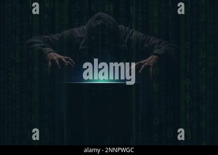 hacker over a screen with green binary code. Crime and Information Theft and Computers Stock Photo