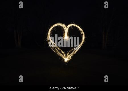 heart shape light painting with sparklers outdoors at night - symbol for love and romance Stock Photo