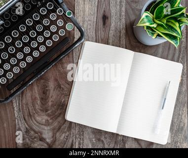top view of vintage typewriter and open diary or note pad on rustic wooden table Stock Photo