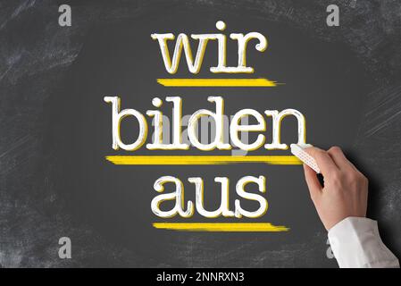 text WIR BILDEN AUS, German for we train apprentices, written on blackboard Stock Photo