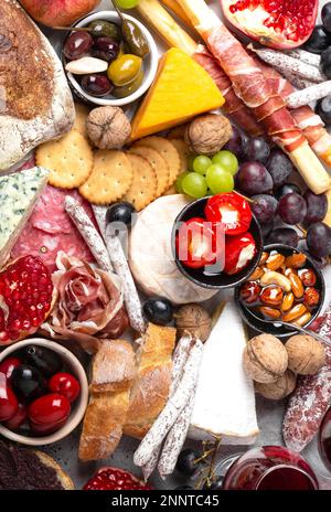 Festive gourmet mix of snacks and appetizers, cheese, meat, olives, bread, fruit, canapes, wine in glasses. Italian antipasti set or Spanish tapas Stock Photo