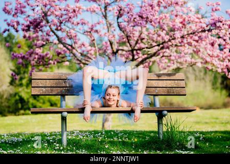 Ballerina in blue dress stretching under cherry blossom, Battle Point Park, Bainbridge Island, Washington, USA Stock Photo