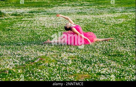 Ballerina doing splits on lawn with flowers, Battle Point Park, Bainbridge Island, Washington, USA Stock Photo