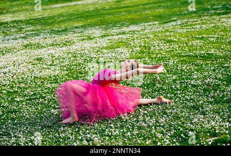 Ballerina doing splits on lawn with flowers, Battle Point Park, Bainbridge Island, Washington, USA Stock Photo