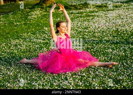 Ballerina doing splits on lawn with flowers, Battle Point Park, Bainbridge Island, Washington, USA Stock Photo