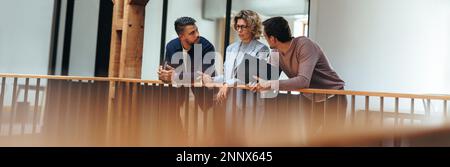 Discussion in an office. Three business people talking on an interior balcony. Group of interior designers team up on a project, they're working in a Stock Photo