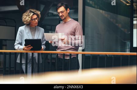 business people reading a document together. Two professionals analyse a financial report in an office. business colleagues discuss with each other wh Stock Photo