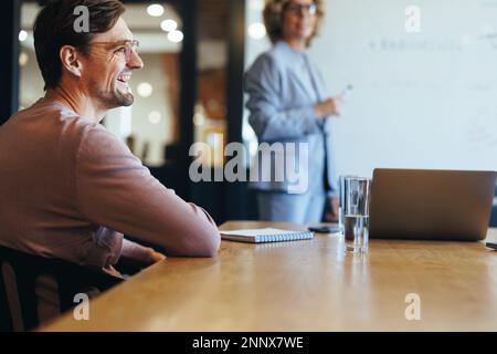 Happy business man sitting in a boardroom meeting with his team. business professional working on a project with his colleagues. Team discussion in an Stock Photo