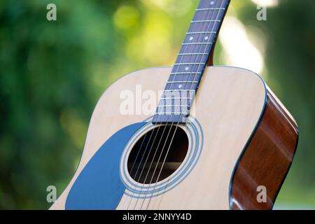 Acoustic guitar outdoors on greenery background. Concept of calm music. Stock Photo