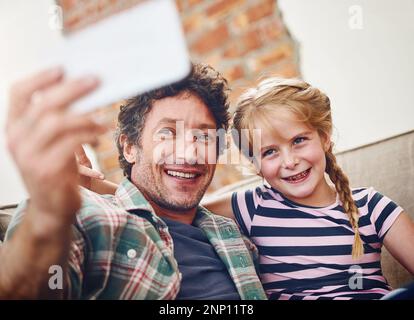 Simple moments can make the best memories. a father and his little daughter taking a selfie together at home. Stock Photo