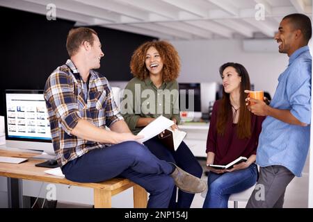 Teamwork holds the capacity for increased office morale. a team of designers having a meeting in an office. Stock Photo