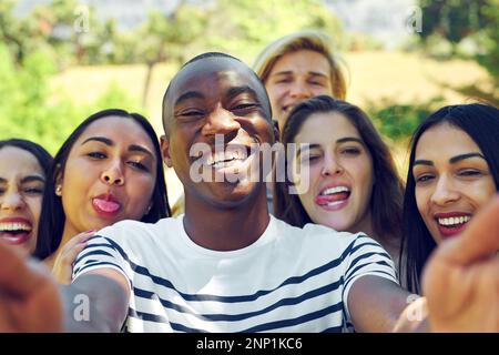 Selfies with my favourites. a group of young friends taking a selfie together outdoors. Stock Photo