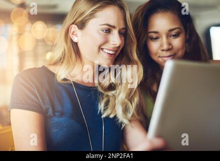 Sharing some online time. girlfriends sharing something on a digital tablet while sitting in a cafe. Stock Photo