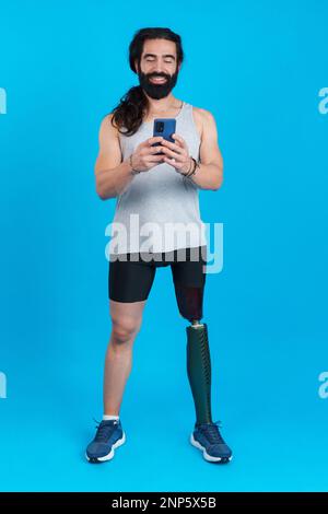 Distracted sportive man with a leg prosthesis using a mobile Stock Photo