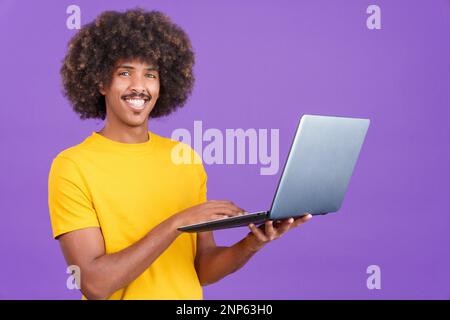 Smiley african man standing and using a laptop Stock Photo