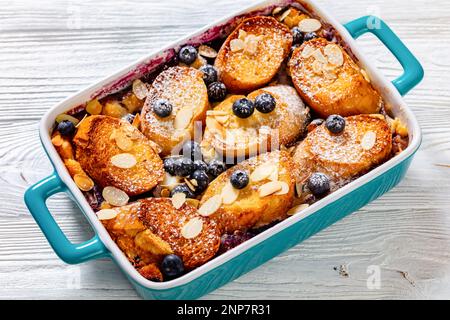 Baked Blueberry Almond Mascarpone French Toast in baking dish on white wood table Stock Photo