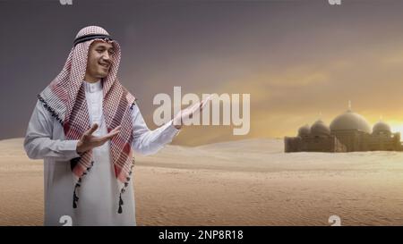 Arab man wearing keffiyeh showing something on his hand with mosque background Stock Photo