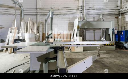 A large sliding table saw machine with dust hood in industrial factory producing wooden furniture parts. Stock Photo