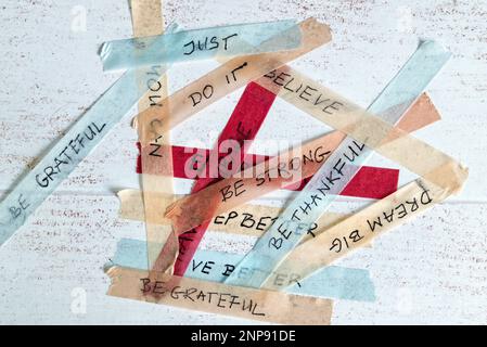 mixed up motivational messages handwritten on colorful washi tape against white wooden background - not sticking to resolutions concept Stock Photo