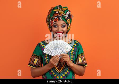 Happy black woman holding money banknotes and smiling Stock Photo