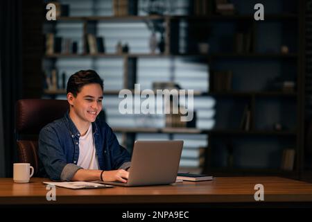Young happy IT specialist working on laptop at office Stock Photo