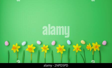 Yellow narcissus and easter eggs on green background. Spring, easter concept. Flat lay, top view, copy space. Stock Photo
