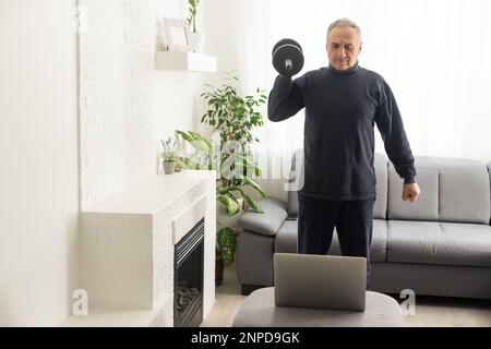 Gray-haired senior man doing online training on a laptop Stock Photo