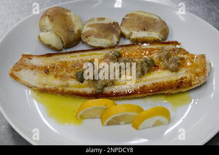 Sole fish with Canarian potatoes and capers sauce, seafood dish with a tasty flavorsome fish, papas arrugadas, a type of small potatoes and capers Stock Photo
