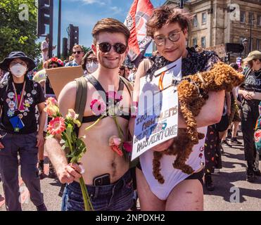 A couple from the LGBTQ+ community poses for the camera with their cute dog as they protest against the lack of rights and healthcare for transgender people in Hyde Park. Stock Photo