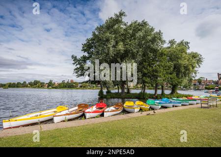 The pretty mere at Thorpeness framed by colourful rowing boats on the Suffolk coastline. Stock Photo