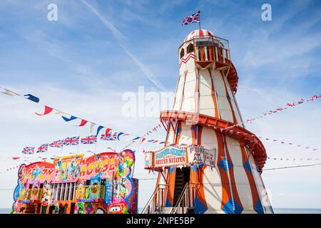 Colourful helter skelter at Hunstanton fairground surrounded by Union Jack bunting. Stock Photo