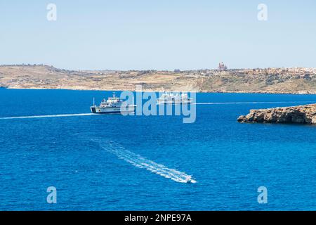 Car ferries crossing between Gozo and Malta pictured from the small island of Comino. Stock Photo