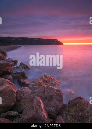 A colourful sunrise over a rocky bay in Dorset. Stock Photo