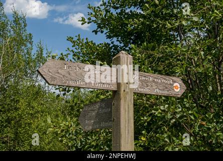 Close up of wooden public footpath sign to the lake and Keswick near Derwentwater in summer. Stock Photo