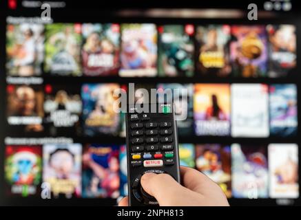 New york, USA - February 21, 2023: Select video on Netflix stream service on tv with remote control in hand Stock Photo