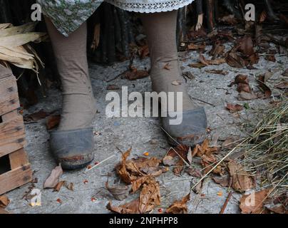 old worn-out slippers at the feet of an old old woman in the courtyard of the rural house Stock Photo