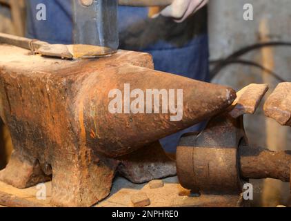 rusted iron anvil and hammer that seems to be moving in the blacksmiths workshop Stock Photo