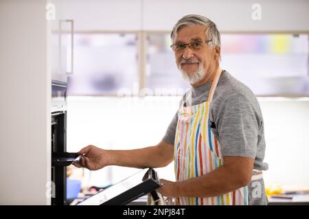 Senior man prepares healthy version of potatoes in the oven Stock Photo