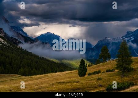 Dark storm clouds building up over the Sexten Dolomites, valleys partially shrouded in clouds, seen from above the pass Passo Falzarego. Stock Photo