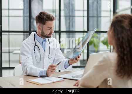Concentrated male doctor looking at x-ray picture of spine Stock Photo
