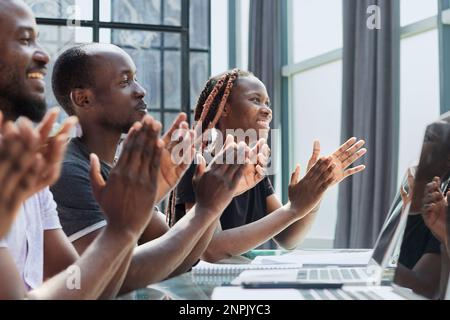 Multi ethnic business group greets somebody with clapping and smiling Stock Photo