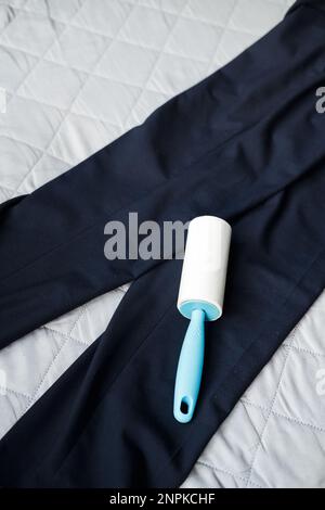 roller for cleaning clothes from dust and pellets on dark trousers, top view Stock Photo