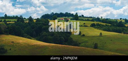 Beautiful picturesque Zlatibor region landscape with distinctive architectural style houses scattered over green hills on sunny summer day Stock Photo