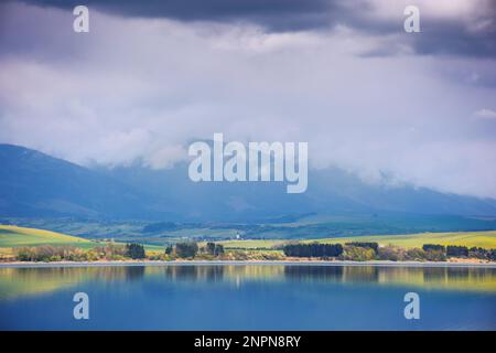lake near the liptovsky mikulas, slovakia. liptovska mara water reserve in front of tatra mountains in spring. beautiful landscape on a cloudy afterno Stock Photo