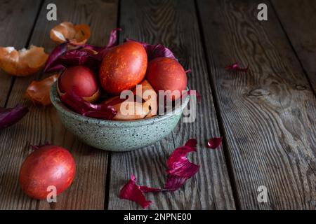 Boiled eggs dyed with onion peel in a bowl on a wooden background. Traditional Easter concept. Stock Photo