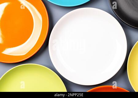 Different clean colorful plates on grey background. Flat lay with copy space Stock Photo
