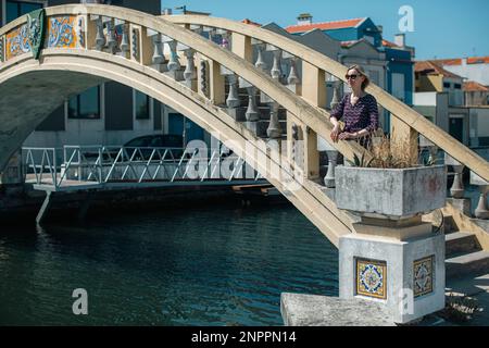 A woman stands near the bridge on Ria de Aveiro canals. Portugal. Stock Photo