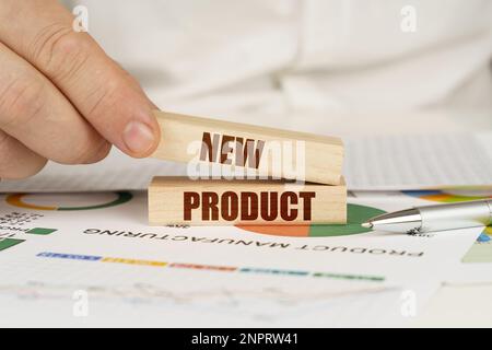 Business concept. On the table are business charts and diagrams in the hands of a wooden block with the inscription - NEW PRODUCT Stock Photo