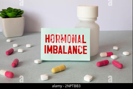 Medical concept. On a brown surface lies a stethoscope, pills and a notepad with the inscription - Hormones Imbalance Stock Photo